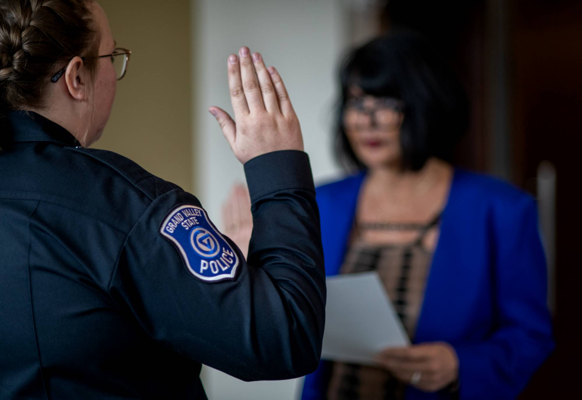 Female police officer raising right hand to swear to oath of office administered by President Mantella